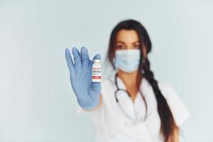 Holding test tube. Young female doctor in uniform is indoors photo