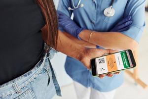 With digital passport. Doctor in uniform making vaccination to the patient photo