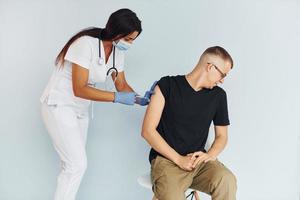 Man is nervous. Doctor in uniform making vaccination to the patient photo