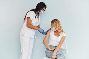 doctor en uniforme vacunando a la mujer foto