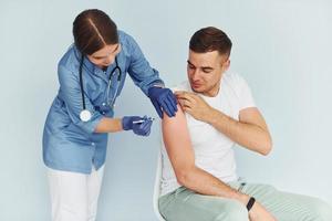 Using syringe. Doctor in uniform making vaccination to the patient photo