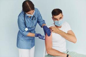 Using syringe. Doctor in uniform making vaccination to the patient photo