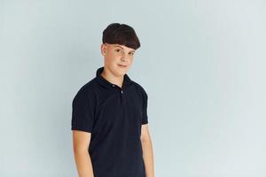 Portrait of young boy in black shirt that posing against white background photo