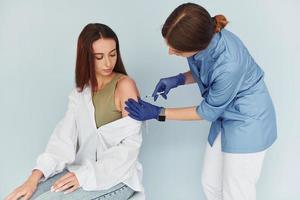 SImple but effective procedure. Doctor in uniform making vaccination to the patient photo