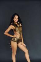 In exotic golden colored wear. Cheerful woman with black curly hair is indoors photo