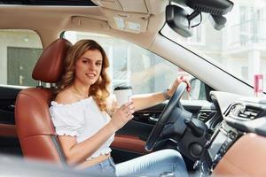 Young woman in casual clothes is sitting in her car at daytime photo