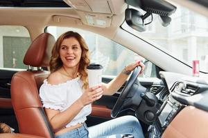 Young woman in casual clothes is sitting in her car at daytime photo