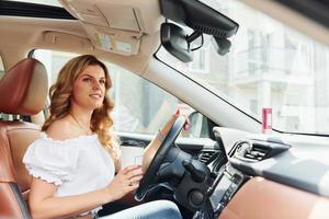 Young woman in casual clothes is sitting in her car at daytime photo