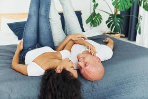 acostada en la cama. una pareja alegre está junta en el interior foto