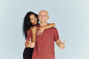 Standing in the studio against white background. Cheerful couple is together indoors photo