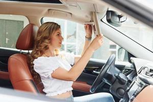 Beautiful young woman in casual clothes is sitting in her car at daytime photo