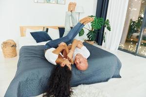 Laying down on the bed. Cheerful couple is together indoors photo