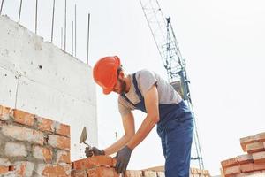 Young construction worker in uniform is busy at the unfinished building photo