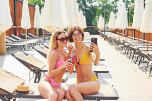 amigos tienen buen tiempo. las mujeres en traje de baño se divierten juntas al aire libre en verano foto