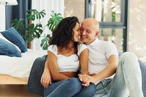 Sitting and embracing each other. Cheerful couple is together indoors photo