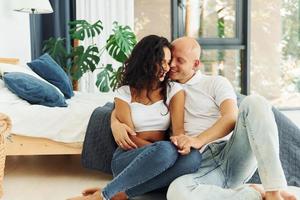 Sitting and embracing each other. Cheerful couple is together indoors photo