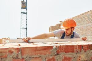 Busy day. Young construction worker in uniform is busy at the unfinished building photo