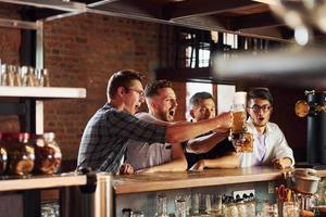 People in casual clothes sitting in the pub and drinking beer photo