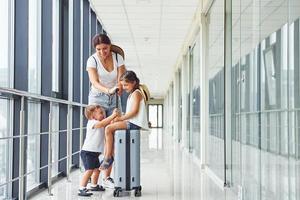 madre con hija e hijo. joven viajero está en el vestíbulo de entrada del aeropuerto foto