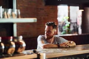 Young man in casual clothes sitting in the pub photo