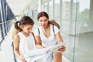 Daughter and mother. Young traveler is on the entrance hall in the airport photo