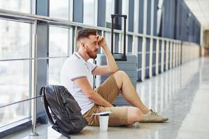 Man is on the ground. Young traveler is on the entrance hall in the airport photo