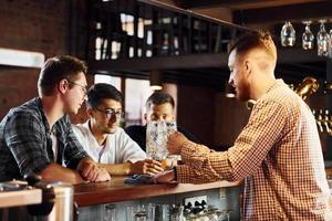 jóvenes alegres con ropa informal sentados en el pub foto