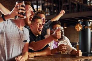 con cerveza en las manos. gente con ropa informal sentada en el pub foto