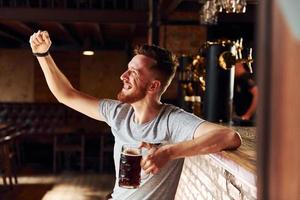 With beer. Man in casual clothes sitting in the pub photo