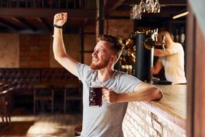 With beer. Man in casual clothes sitting in the pub photo