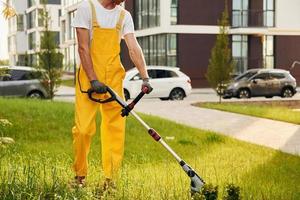 Building exterior at background. Man cut the grass with lawn mover outdoors in the yard photo
