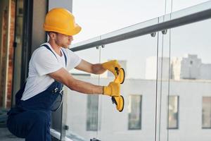 Installation of windows. Young man working in uniform at construction at daytime photo