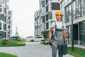 Finished buildings. Young man working in uniform at construction at daytime photo