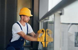 instalación de ventanas. joven que trabaja en uniforme en la construcción durante el día foto