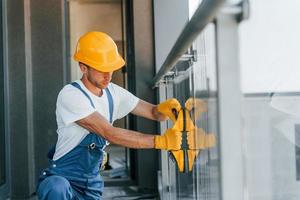 Installation of windows. Young man working in uniform at construction at daytime photo