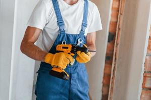 Empty walls. Young man working in uniform at construction at daytime photo