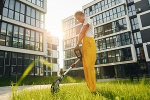 Beautiful sunshine. Man cut the grass with lawn mover outdoors in the yard photo