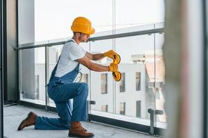 Installation of windows. Young man working in uniform at construction at daytime photo