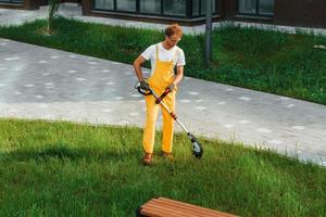 Distant view. Man cut the grass with lawn mover outdoors in the yard photo