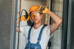 en ropa protectora. joven que trabaja en uniforme en la construcción durante el día foto