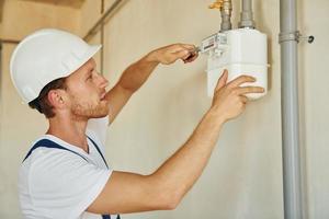 Repaiting the pipes. Young man working in uniform at construction at daytime photo