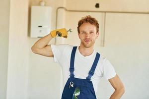 Professional occupation. Young man working in uniform at construction at daytime photo