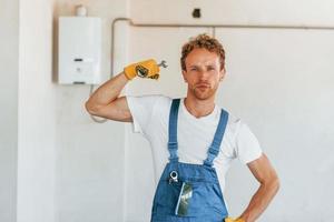 Professional occupation. Young man working in uniform at construction at daytime photo