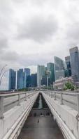 vista de estrada de rua timelapse vertical leva a arranha-céus edifícios de negócios financeiros modernos cbd famosa área de distrito de singapura na área de marina bay com nublado movendo-se no céu video