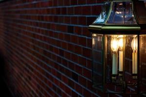 Lamp mounted on a brick wall illuminating golden light photo