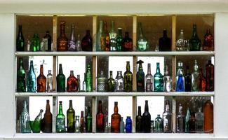 Many empty colorful glass bottles displayed inside a window photo