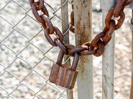 Old rusty heavy duty pad lock and chain on a fence photo