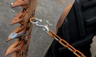 Vintage antique automotive tractor wheel and cutter implement and chain showing rust photo