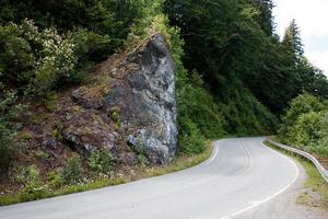 Curvy highway bending around a rocky corner with trees photo