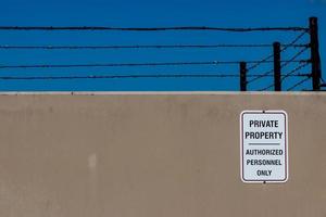 Concrete wall with a private property sign and barbed wire photo